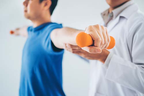health professional guiding a patient through exercises with an orange dumbbell