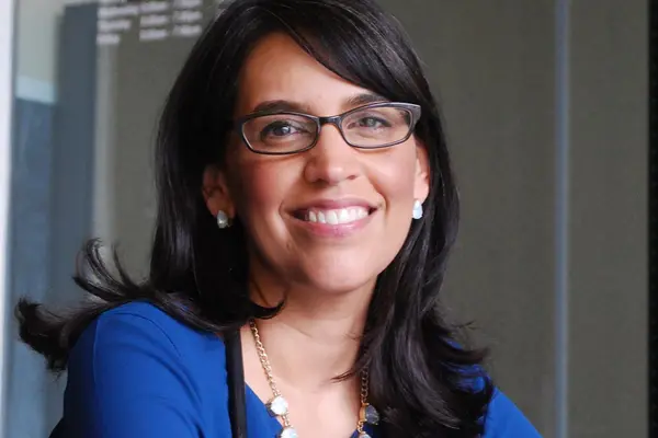 Dr. Eva Galvez smiles for the camera, wearing a blue top and with a stethoscope looped around her neck