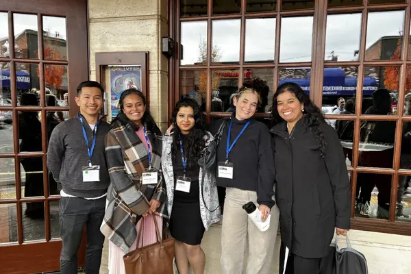 Devika Dhamija and partners pose wearing business attire and namebadges on lanyards while attending the Venture Partners Fund copmetition.