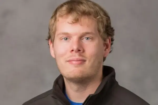 Chris Hauck, wearing a black shirt, poses against a neutral grey background