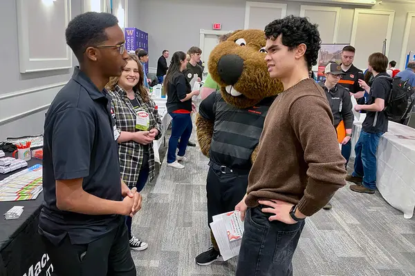 Benny the Beaver and an OSU student chat with employers at a career fair